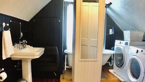 Une salle de bain compacte et bien éclairée, équipée d’un lavabo, de toilettes et d’une petite machine à laver.
