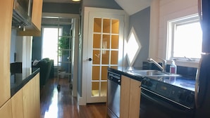Une cuisine avec des meubles de rangement en bois, un lave-vaisselle, une cuisinière et une fenêtre.