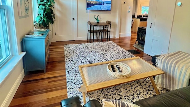Un vaste salon doté d’un plafond en bois, d’un grand téléviseur fixé au mur, d’une table à manger avec des chaises, d’un canapé et d’une cheminée en arrière-plan.