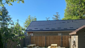 Un espace extérieur aménagé avec des tables de pique-nique et un petit bâtiment doté d’un toit en tuiles.