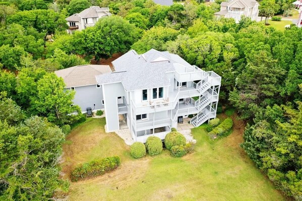 A multi-story house surrounded by dense greenery. - Beautiful Emerald Isle Ocean Side Home, Steps from the Beach (Emerald Isle)