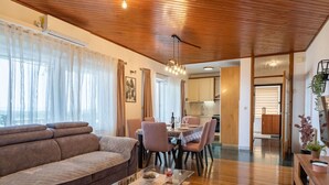 Una sala de estar moderna con techo de madera, un sofá, una mesa de centro de vidrio y un comedor con sillas y una mesa.