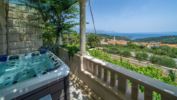 Un jacuzzi en un balcón con vistas a un pueblo costero y montañas.