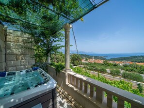Een bubbelbad op een balkon met uitzicht op een kustplaatsje en bergen.