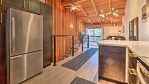 A modern kitchen with a stainless steel refrigerator, wooden cabinets, and a wooden ceiling.