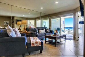 Relax in this stylish living room with a sofa, coffee table, and large mirror, offering a view of the ocean from the balcony.