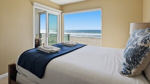 Une chambre avec un lit, une vue sur la plage et une porte donnant sur un espace extérieur.