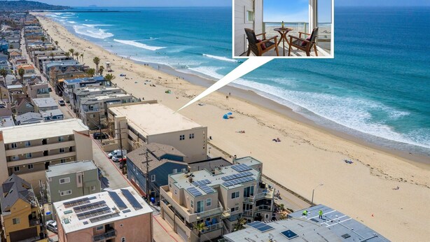 Un hôtel en bord de mer doté d’un balcon donnant sur la plage, avec vue sur l’océan, et d’une petite image encadrée représentant une chambre avec une table et des chaises.