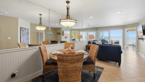 Un coin repas avec des chaises en osier, une table ronde et des luminaires suspendus.
