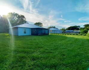 A residential property with a large lawn, a house with a metal roof, and a covered outdoor area. - Vero's Cove  (Vero Beach)