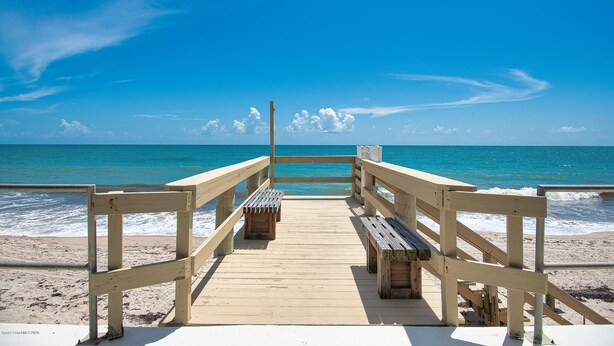 A wooden pier leading to a beach with benches and a railing. - Vero's Cove  (Vero Beach)
