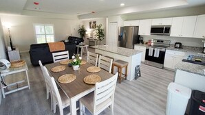 A modern kitchen with white cabinets, a stainless steel refrigerator, and a microwave. - Vero's Cove  (Vero Beach)