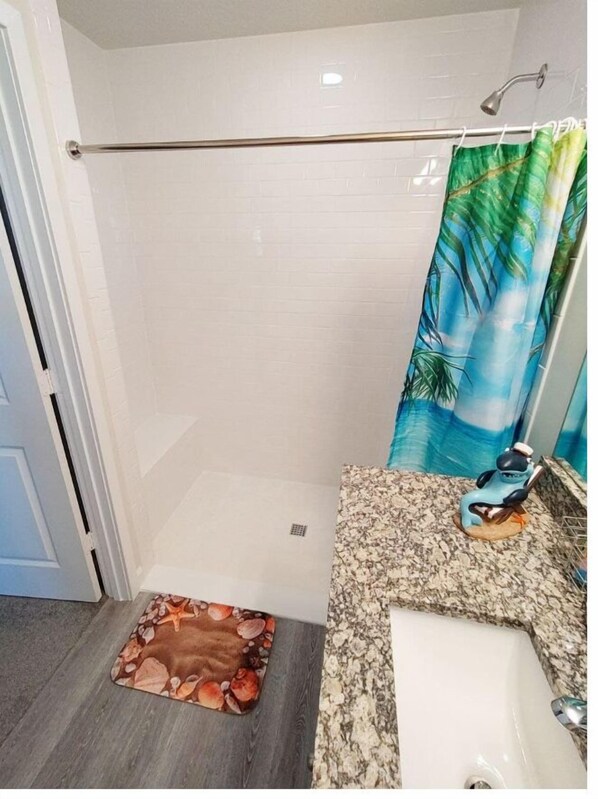 A bathroom with a shower, a sink, and a toilet.