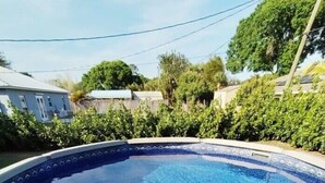 A swimming pool with a clear blue water surface, surrounded by a white pool deck and safety railings. - Vero's Cove  (Vero Beach)
