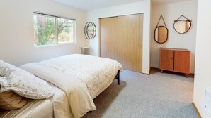 A bedroom with a bed, a wooden wardrobe, a radiator, and a window with a view of trees. - Wander in to Alpine, a basecamp for your adventure!! (Leavenworth)