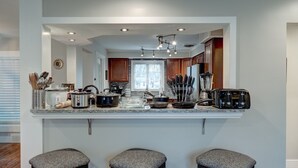 Uma cozinha moderna com ilha central, iluminação embutida e janela que proporciona luz natural.