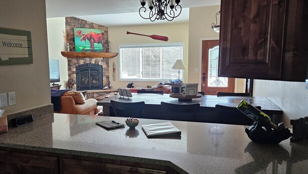A kitchen with a stone fireplace, a dining area with a large table, and a living room with a couch.