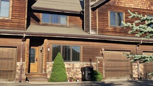 A two-story wooden house with a gabled roof, a chimney, and a garage with two doors.