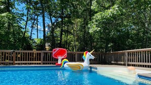 Une piscine avec un flotteur en forme de licorne et un panier de basketball.