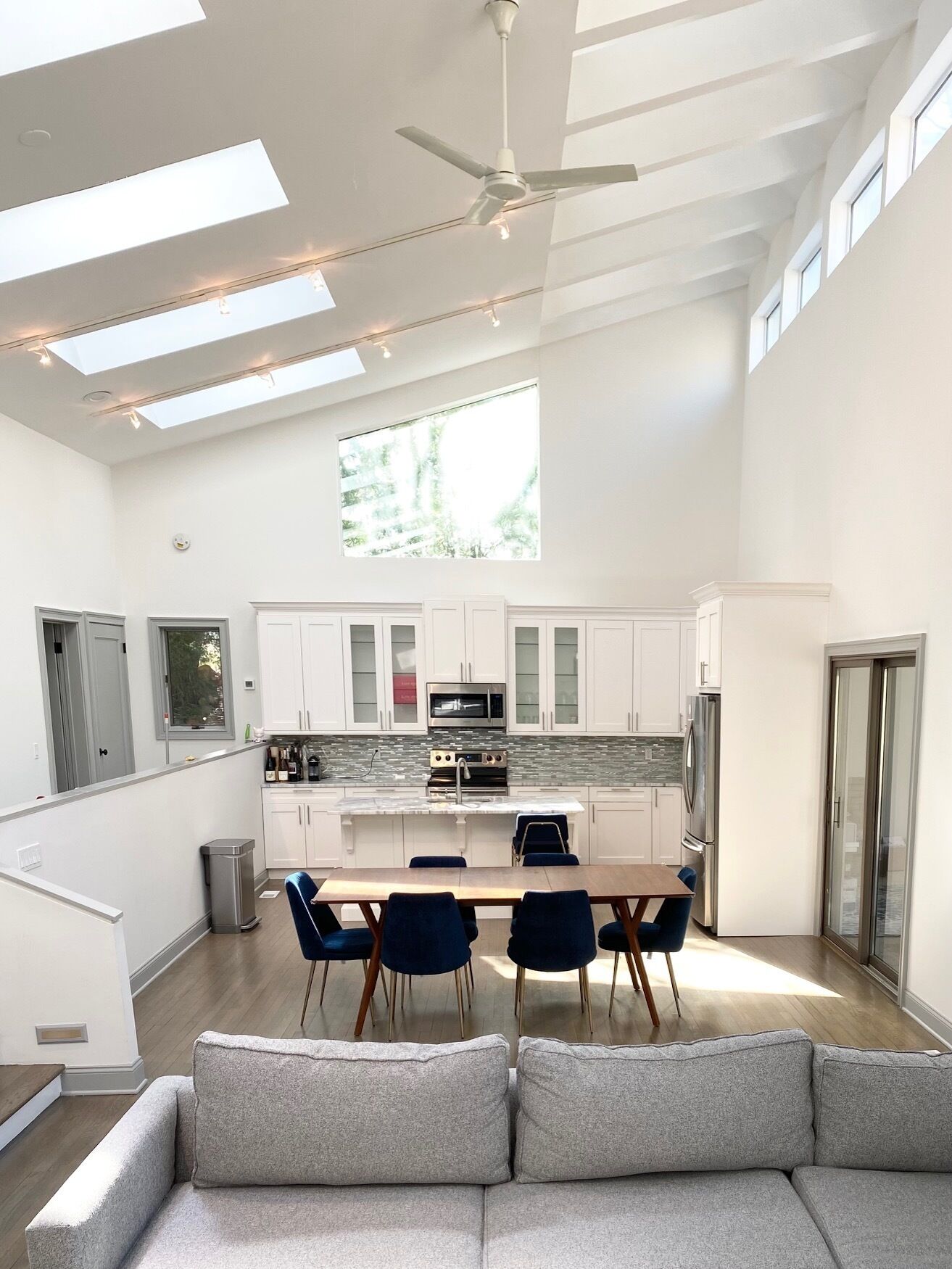 A modern kitchen with white cabinets, a central island, and a dining area with blue chairs.