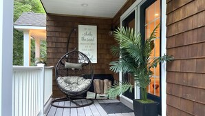 A wooden deck with a hanging chair and a potted plant.