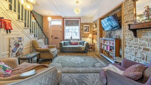 A cozy living room with a staircase, a fireplace, a television, and a bookshelf. - Hebden Bridge - House - Sleeps 8 - Pet Friendly (Hebden Bridge)