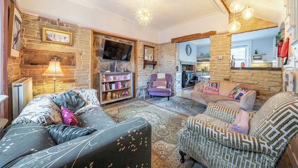 A cozy living room with a fireplace, a television, and a kitchen area visible through an open door. - Hebden Bridge - House - Sleeps 8 - Pet Friendly (Hebden Bridge)