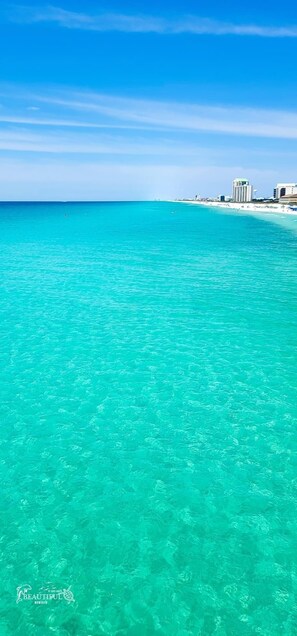 Ein Strand mit klarem türkisblauem Wasser und einer entfernten Skyline.