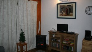 A living room with a fireplace, a bookshelf, a television, and a clock on the wall.