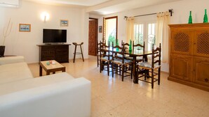 A living room with a sofa, a TV, a dining table with chairs, and a wooden cabinet. - Vacation home La Paz by Interhome (Calpe/Calp)