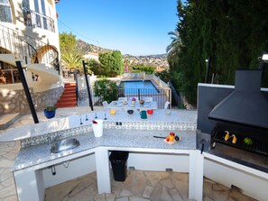 An outdoor kitchen with a pool in the background. - Vacation home La Paz by Interhome (Calpe/Calp)