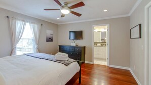 A bedroom with a bed, a dresser, a ceiling fan, and a bathroom visible through an open door. - Metropolitan City Home - Huge Private Backyard (Nashville)
