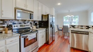 A modern kitchen with white cabinets, stainless steel appliances, and a wooden floor. - Metropolitan City Home - Huge Private Backyard (Nashville)