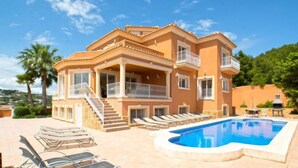 Une maison à plusieurs étages dotée d’une piscine, d’un espace salon extérieur et d’un escalier menant aux étages supérieurs.