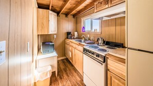 A compact kitchen with wooden cabinets, a stove, and a refrigerator.