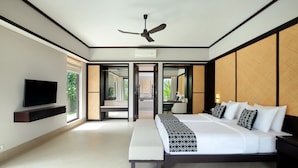 Une chambre d’hôtel moderne dotée d’un grand lit, d’un ventilateur de plafond, d’un téléviseur à écran plat et offrant une vue sur l’extérieur.