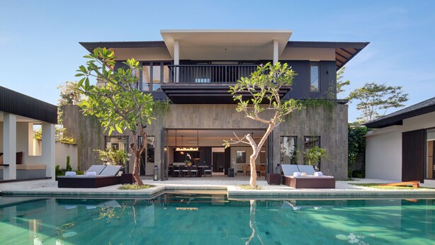 Une maison moderne à deux étages dotée d’une piscine, d’un espace salon extérieur et d’un balcon.
