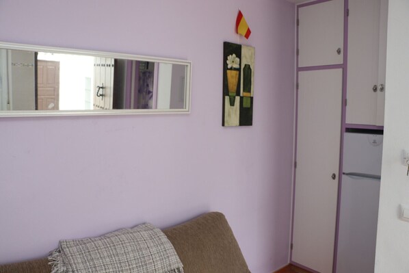 A room with a bed, a wardrobe, a mirror, and a painting on the wall.