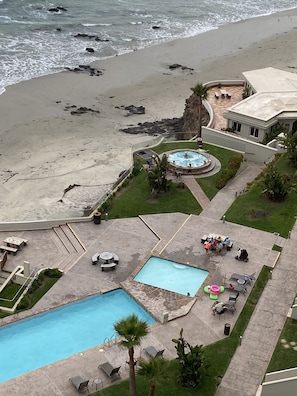 Un complex turístic amb piscina, zona de seients a l'aire lliure i vistes a la platja.