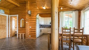 Interior de una cabaña de troncos con cocina, comedor y baño.