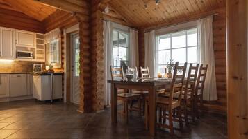 A log cabin interior with a kitchen, dining area, and large windows.