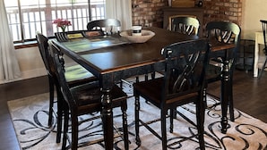 Comedor con pared de ladrillo, chimenea y un amplio ventanal con cortinas.