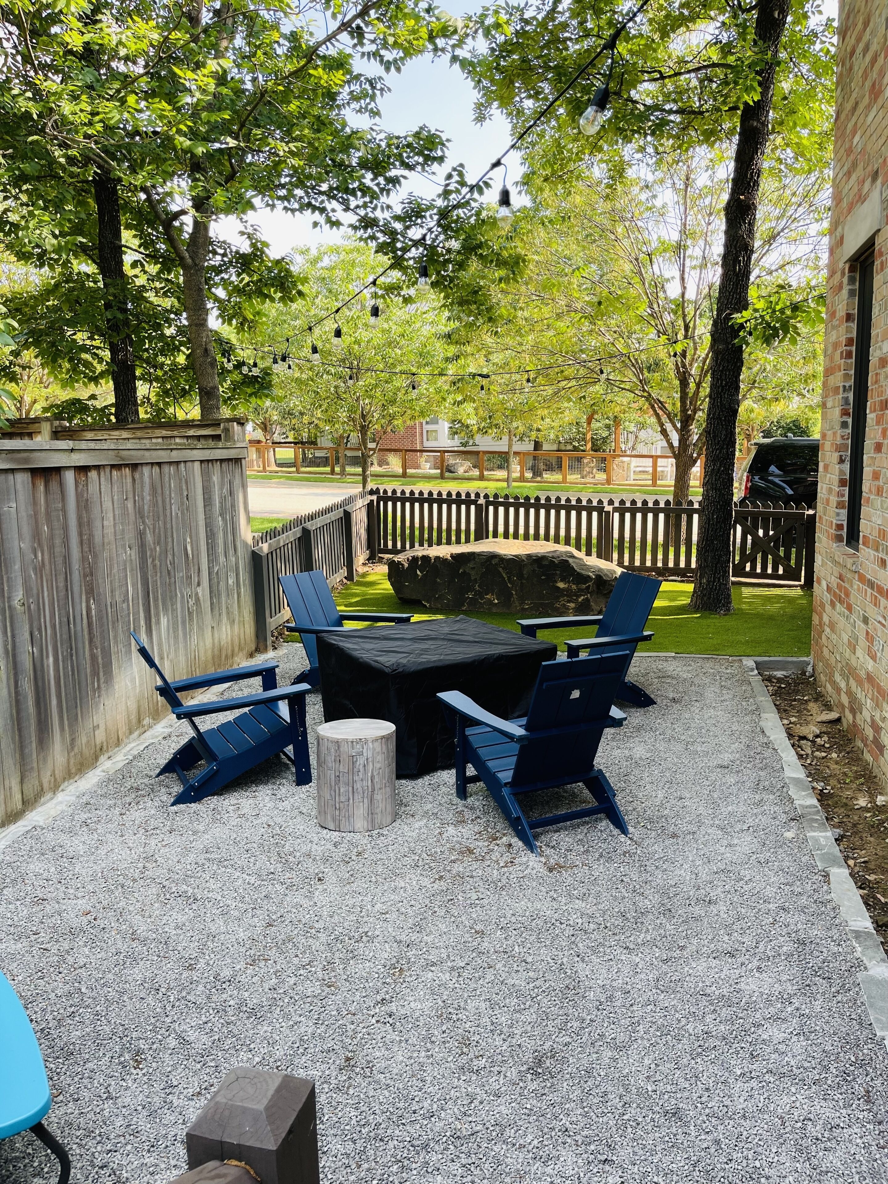 Une terrasse extérieure avec une table et des chaises, entourée d’une clôture en bois et d’arbres.