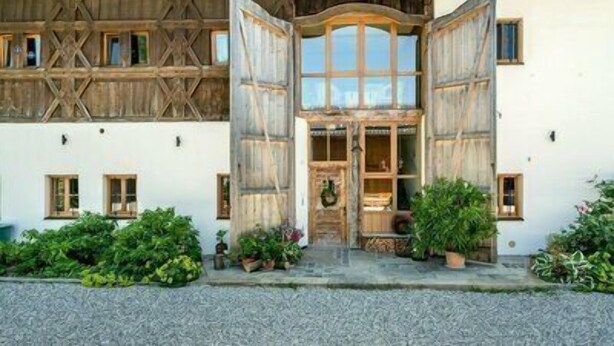 A traditional chalet with wooden shutters, a stone facade, and a welcoming entrance. - Ferienwohnung Obstgarten, 47 qm 1. Stock, 1 Separates Schlafzimmer (Höslwang)