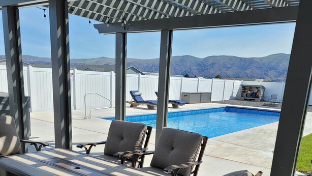 En uteplats med en pool, solstolar och ett bord.