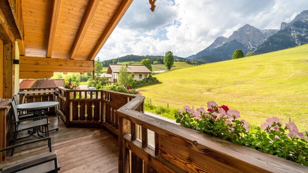 A wooden deck with outdoor seating, overlooking a green field and mountains. - Very attractive and well cared for apartment (Maria Alm)