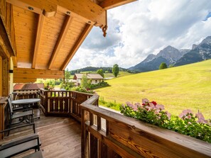 A wooden deck with outdoor seating, overlooking a green field and mountains. - Very attractive and well cared for apartment (Maria Alm)