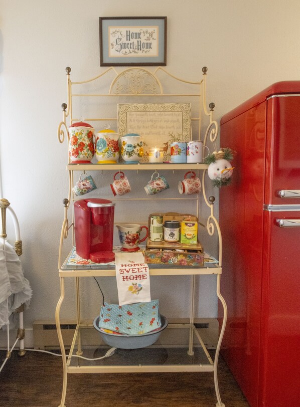 A metal shelf with various kitchen items, a framed sign above, and a red cabinet to the right. - “SWEET ROSE” Cottage! Vintage Glam! GOG, Horses, Manitou! (Colorado Springs)