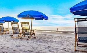 Relax on the beach with comfortable chairs and shaded umbrellas overlooking the ocean.