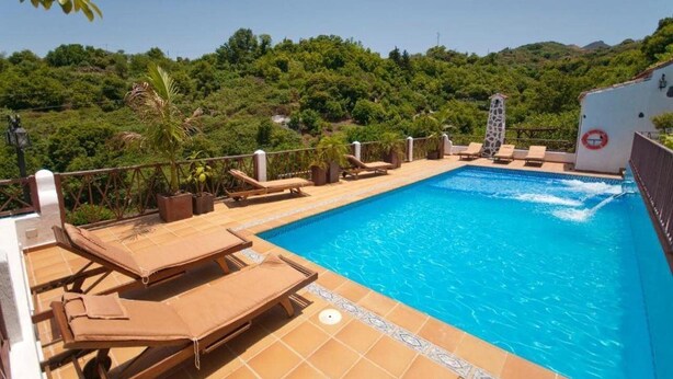 A swimming pool with lounge chairs and a view of a lush green hillside. - Finca Casa Nanita B (Moya)